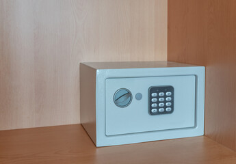 A small metal safe inside a cabinet with password buttons to store valuables. The concept is the purchase of a cash box.