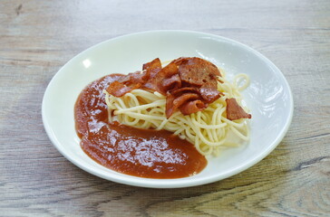 steamed spaghetti with tomato sauce topping slice crispy pork sausage bacon on plate   