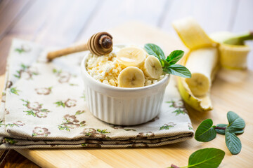 crumbly organic cottage cheese with honey and bananas in a ceramic bowl