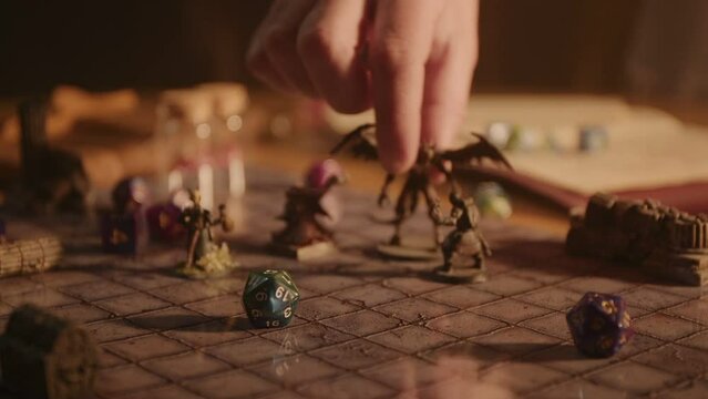 A person plays a fantasy roleplaying game, moving miniatures and rolling dice