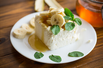 Portion of homemade milk curd with banana slices and honey