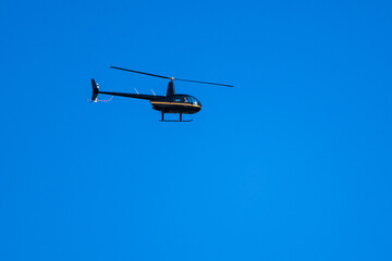 Black helicopter flying in clear blue sky