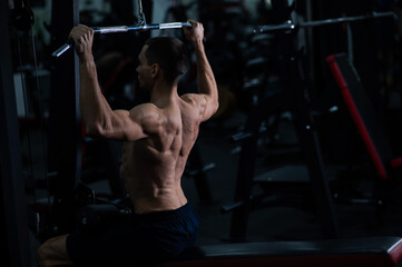 Fototapeta na wymiar A man does a chest pulldown in the gym.