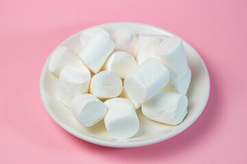 Fototapeta na wymiar Plate with vanilla marshmallows on a pink background.