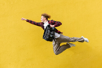 young guy student with backpack flies forward and hurries to study, man jumps and runs in the air