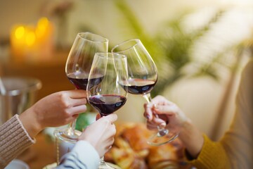 Cheerful friends enjoying home Birthday holiday party. Asian Friends cheering drinking red wine...