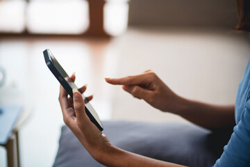 Asian Woman controlling smart home. mobile phone with smart home app in living room. touch screen...