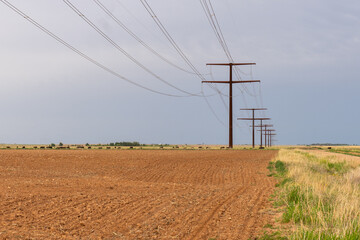 High power line supported by a row of towers through a plowed field, Quitaque, Texas