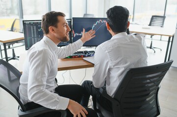 Two diverse crypto traders brokers stock exchange market investors discussing trading charts research reports growth using pc computer looking at screen analyzing invest strategy, financial risks.