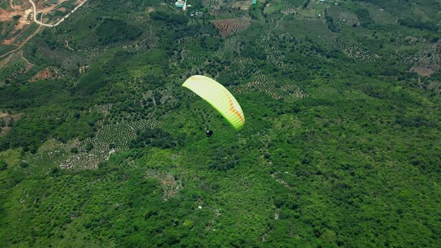 Extreme and active leisure. Man flies on an extreme paraglider in the Vietnamese mountains, the concept of freedom. Paraglider flies above the treetops. 4K