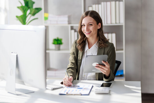 Concept of business office woman working,Businesswoman smile while working about her invesment plan with analyzing document and business investment graph data by using laptop on desk in workstation.