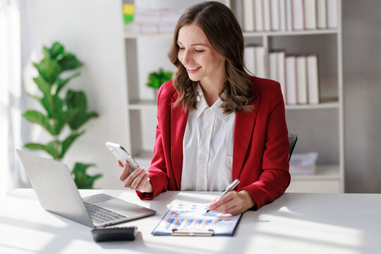 Concept of business office woman working,Businesswoman smile while working about her invesment plan with analyzing document and business investment graph data by using laptop on desk in workstation.