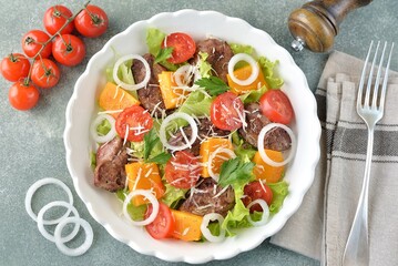 Salad with chicken liver, pumpkin, cherry tomatoes, onions, lettuce and parmesan