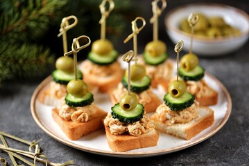 Canapes with cod liver paste and boiled egg, cucumber and olives