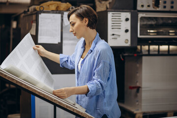 Woman working in printing house with paper and paints