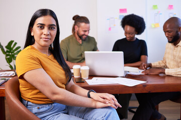 Serious portrait of Indian woman during creative team meeting at boardroom table