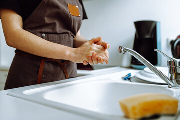 close-up hands woman dishwasher in kitchen while washing dishes