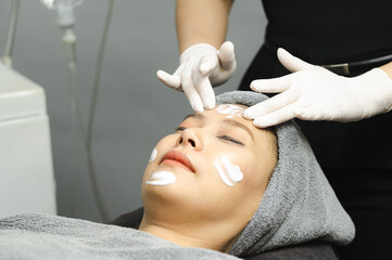 Young woman getting facial mask by professionals in beauty clinic.