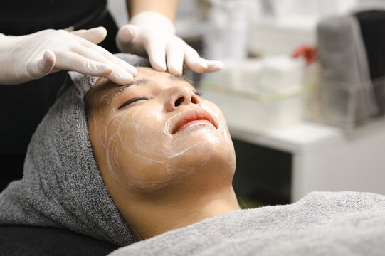 Young woman getting facial mask by professionals in beauty clinic.