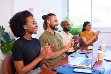 Four diverse team members clapping hands at meeting presentation, tech team