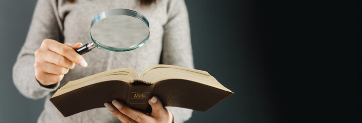 Woman looking at a bible with a magnifying glass