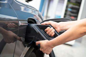 Action of person hand is plugging the CCS2 DC charger socket head with the EV car for recharging...