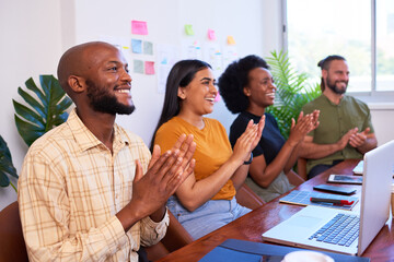 Four diverse team members clapping hands at meeting presentation, tech team