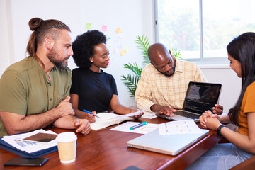Diverse development team discusses code during code review meeting, programming