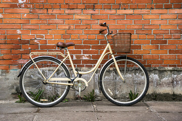 Naklejka premium lady's city bike with a basket leaning against the brick wall