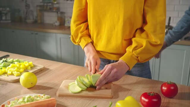Selective focus on hands of young woman slicing vegetable marrow, preparing healthy vegetarian meal