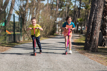 Active kids riding kick scooters in suburbs