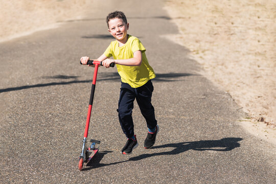 Cheerful boy riding kick scooter