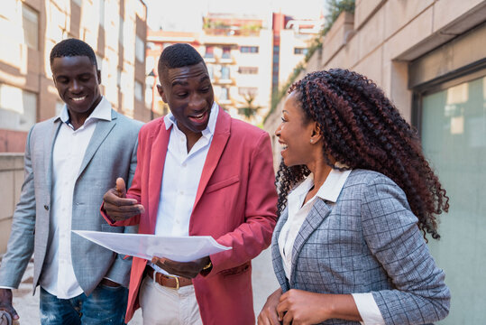 Positive black coworkers examining papers during stroll