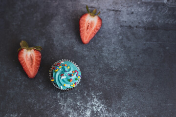 Obraz na płótnie Canvas On a textured dark background, cakes and strawberries.