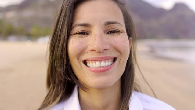 Happy latin woman smiling on camera with beach on bacgkround - Summer travel lifestyle concept