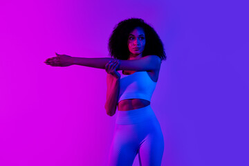 Photo of focused pretty fitness club coach trainer stretch hand wear top leggings isolated on pink blue color neon background
