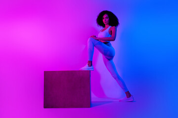 Full body photo pilates trainer woman stretching platform box advertise her new sportswear isolated over blue pink neon filter background