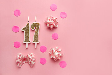 Number 17 on a pastel pink background with festive decor. Happy birthday candles. The concept of celebrating a birthday, anniversary, important date, holiday. Copy space. Banner