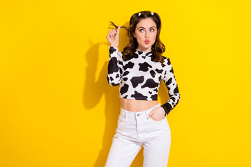 Photo of millennial tricky girl pouty lips flirty play curls look empty space find partner boyfriend isolated on yellow color background