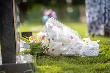 selective focus of flowers in a wrapper on the ground- funeral bouquet on a tombstone in a cemetery