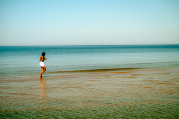 Obraz premium Woman walking in shallow water by beach