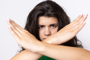 Fototapeta premium Portrait of a serious young woman showing stop gesture with her palm over white background