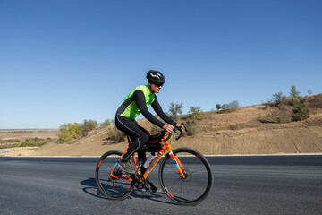 Obraz na płótnie Canvas Cyclist riding bicycle on road against clear sky