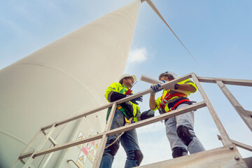 male blueprint froman and male engineer Workers wearing safety jackets looking at power generation turbines plan  repair station wind turbines in the turbine field. Renewable energy concept