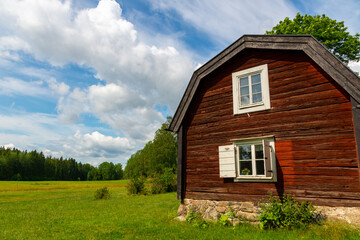 Fototapeta na wymiar Old traditional red house on a swedish farm on a sunny summer day with clouds in the sky.