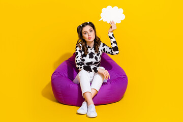 Photo of cute funky lady dressed cowskin shirt sitting bean bag holding mind cloud empty space isolated yellow color background