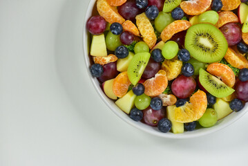 Healthy fresh fruit salad bowl on white background. Top view. Healthy food concept, healthy high vitamin fruit, mixed fruit background.