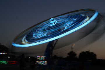  A fast spinning  carousel. Colorful lights, bustling crowds, and a festive ambiance set the stage...