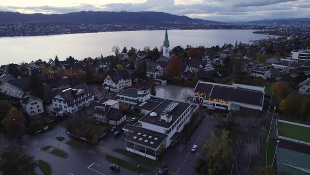 Aerial panoramic drone view of Uetikon and local church, Reformierte Kirchgemeinde Zollikon, with Zurich in the background, Zollikon, Canton of Zurich, Switzerland