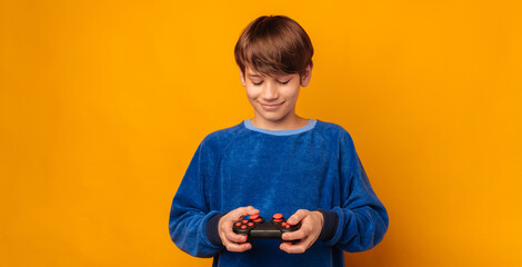 Happy teen boy wearing blue is holding a joystick and playing with it.